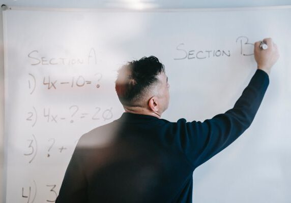 A man writing on the wall with white paint.