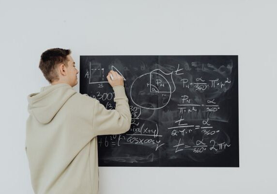 A man writing on the blackboard with chalk.