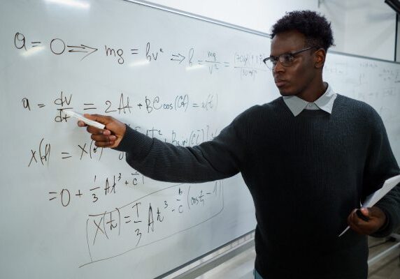 Math MileMarkers® A man standing in front of a white board.